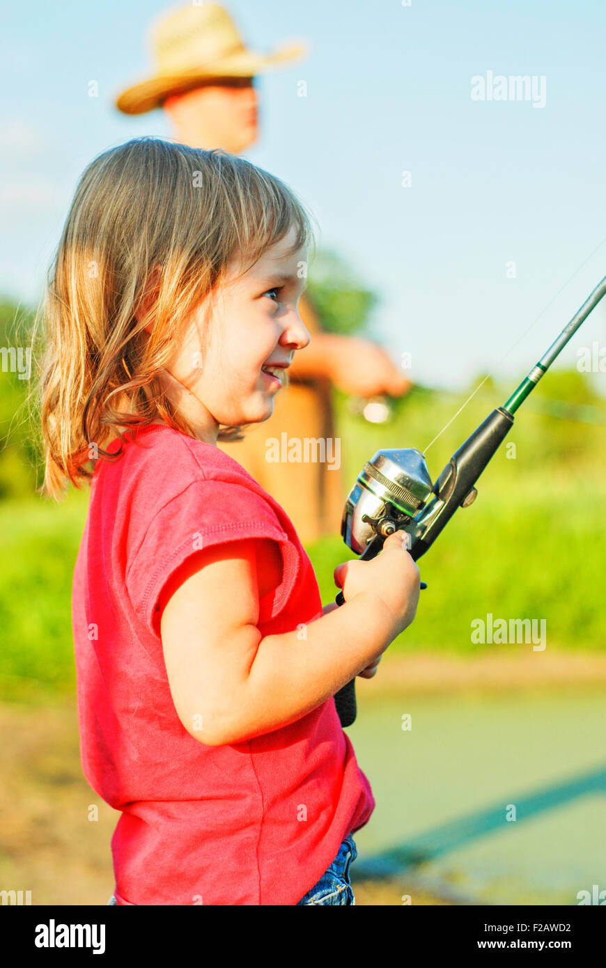 Petite fille avec canne et moulinet de pêche à l'étang Banque D'Images