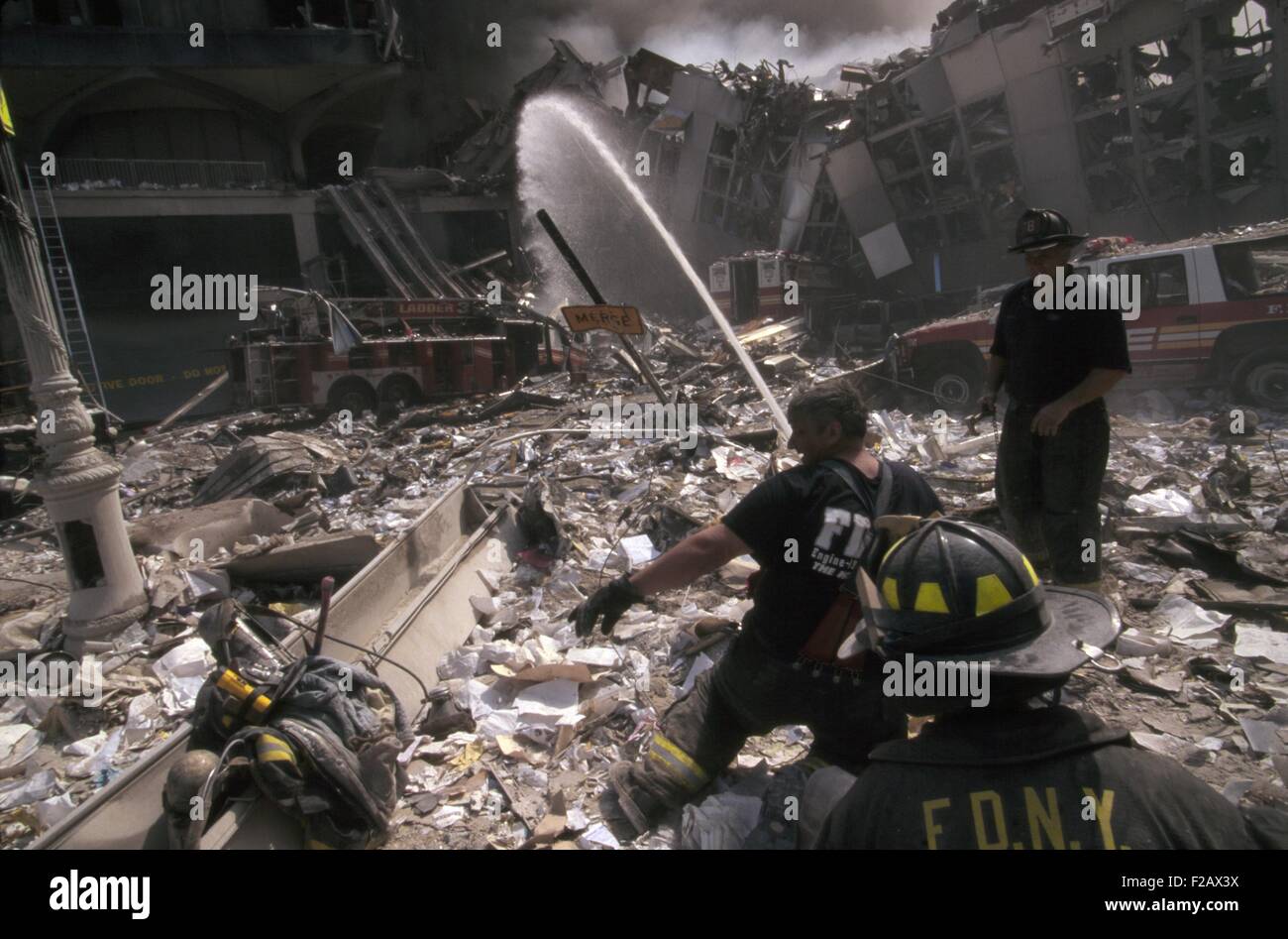 Les pompiers mis en place un tuyau au milieu des décombres de fumer depuis le 11 septembre 2001 attaque terroriste du World Trade Center. À gauche est toujours debout WTC 6. Sur la droite se trouve le Nord détruit passerelle au-dessus de l'autoroute côté ouest (West St.). Le courant d'eau est destiné à l'entre-deux, à l'incendie de la pile s'effondre WTC1 (Tour nord). La ville de New York, le 11 septembre 2001. (BSLOC 2015 2 49) Banque D'Images