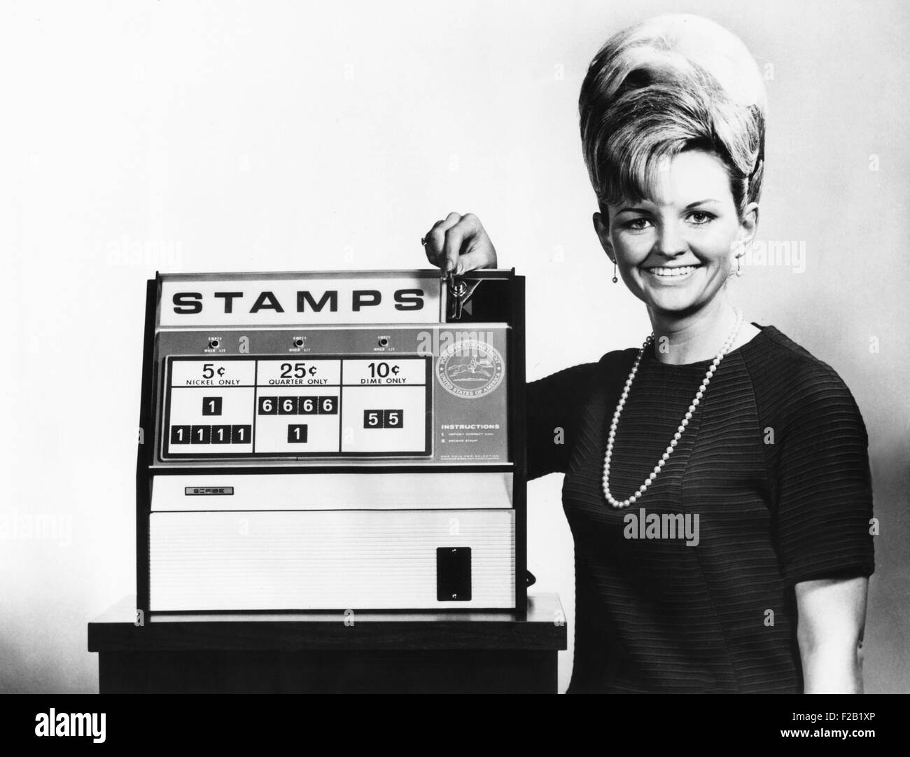 Nouveau ministère des Postes distributeur automatique de timbres à tester à Washington D.C. Betty Johnson, insère un trimestre dans le distributeur automatique de timbres. 7 février 1968. CSU (2015  7 391) Banque D'Images