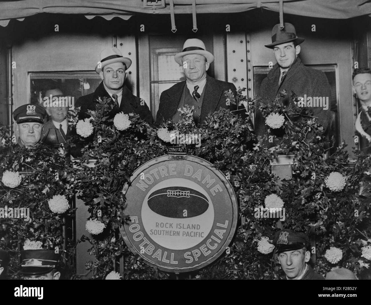 Knute Rockne debout sur l'arrière du train voiture décorée de fleurs, 1930. Rockne est flanquée par l'entraîneur Frank Cariedo et football player Tom Conley comme ils partent pour la Californie. - BSLOC__2015 (1_118) Banque D'Images