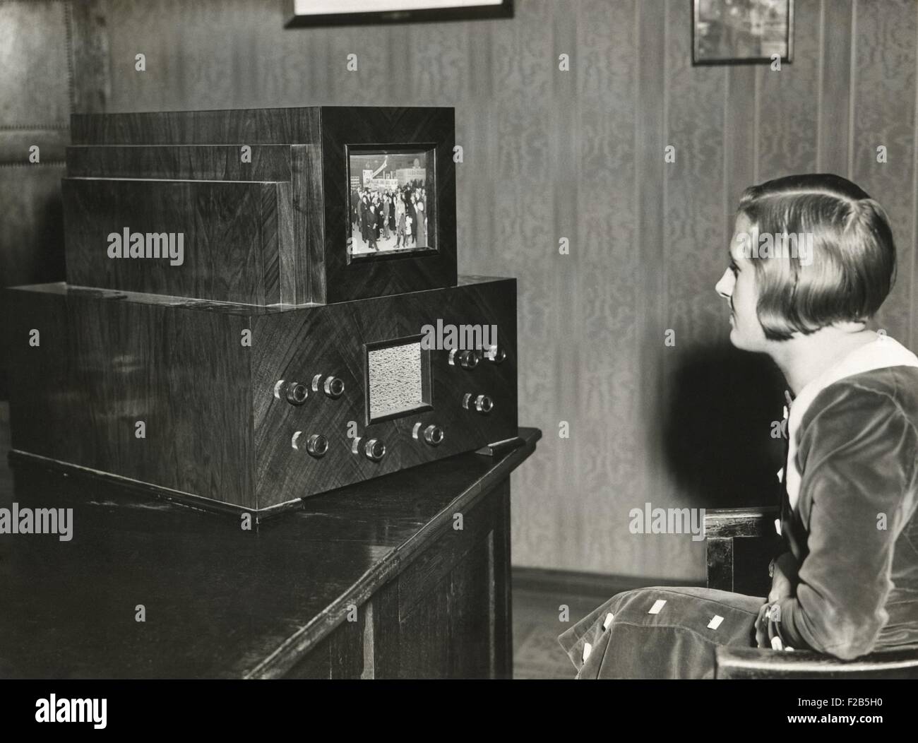 Femme regardant une télévision allemande avec un écran de 14 x 18 centimètres. Transmission des événements en direct n'était pas encore possible. Au lieu de cela, les événements ont été filmés avec ces images en mouvement et sont diffusées à 25 images par seconde à partir d'une station spéciale qui possède la lumière vive. Ca. L'année 1930. - BSLOC  2014 (17 131) Banque D'Images