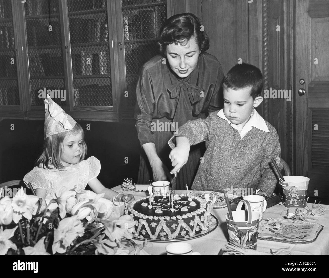 David Eisenhower, le petit-fils de 5 ans, la coupe son gâteau d'anniversaire. Le 30 mars 1953. L-R : Sœur Barbara Anne, mère Barbara Eisenhower, et sœur Barbara Ann. - BSLOC  2014 (16 108) Banque D'Images
