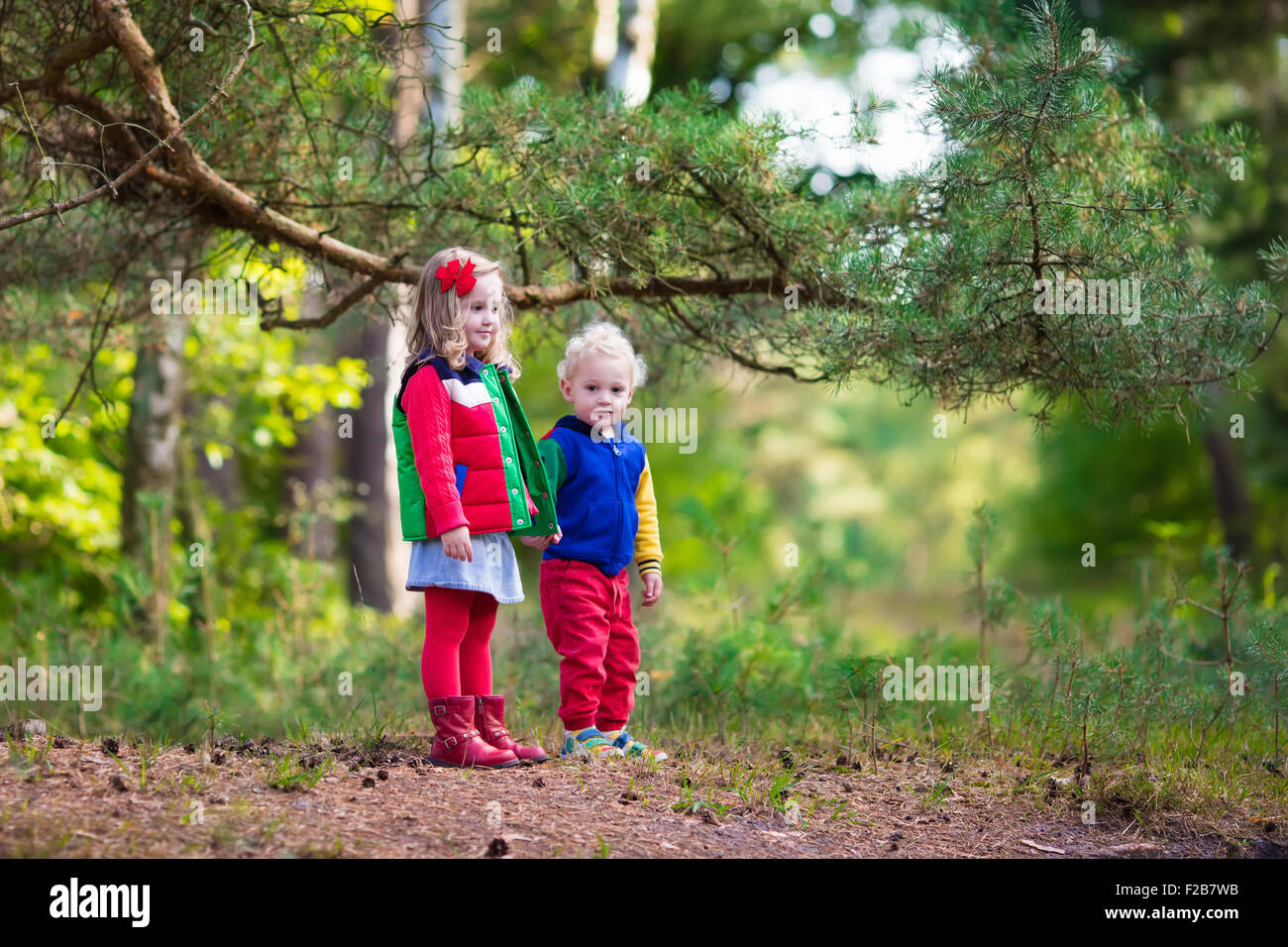 Les enfants jouant dans le parc de l'automne. Les enfants jouent à l'extérieur sur une journée d'automne ensoleillée. Garçon et fille courir main dans la main dans une forêt. Banque D'Images