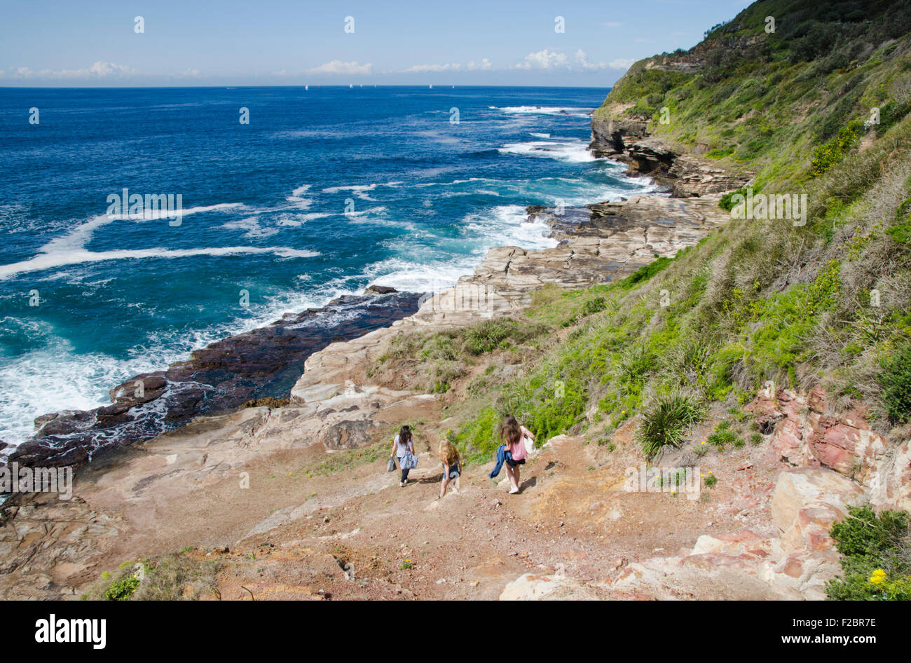 Trois adolescentes et des mains vers le bas de la tête de falaise Turimetta beach Warriewood au NSW Australie Banque D'Images