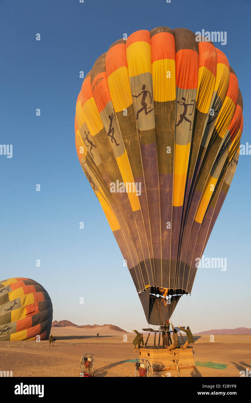 Gonflage pilote de ballon à air chaud avec deux brûleurs, la préparation pour le décollage au lever du soleil, deuxième derrière un ballon, Désert du Namib Banque D'Images