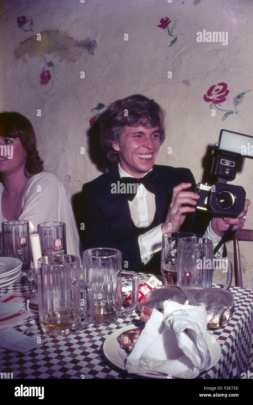 Der Deutsche Schlagersänger Jürgen Marcus bei einer Abendveranstaltung mit einer Kamera, Deutschland 1970 er Jahre. Schlager allemand Juergen chanteur Marcus à l'aide d'une caméra à une soirée, l'Allemagne des années 1970. 24x36DiaV1 Banque D'Images