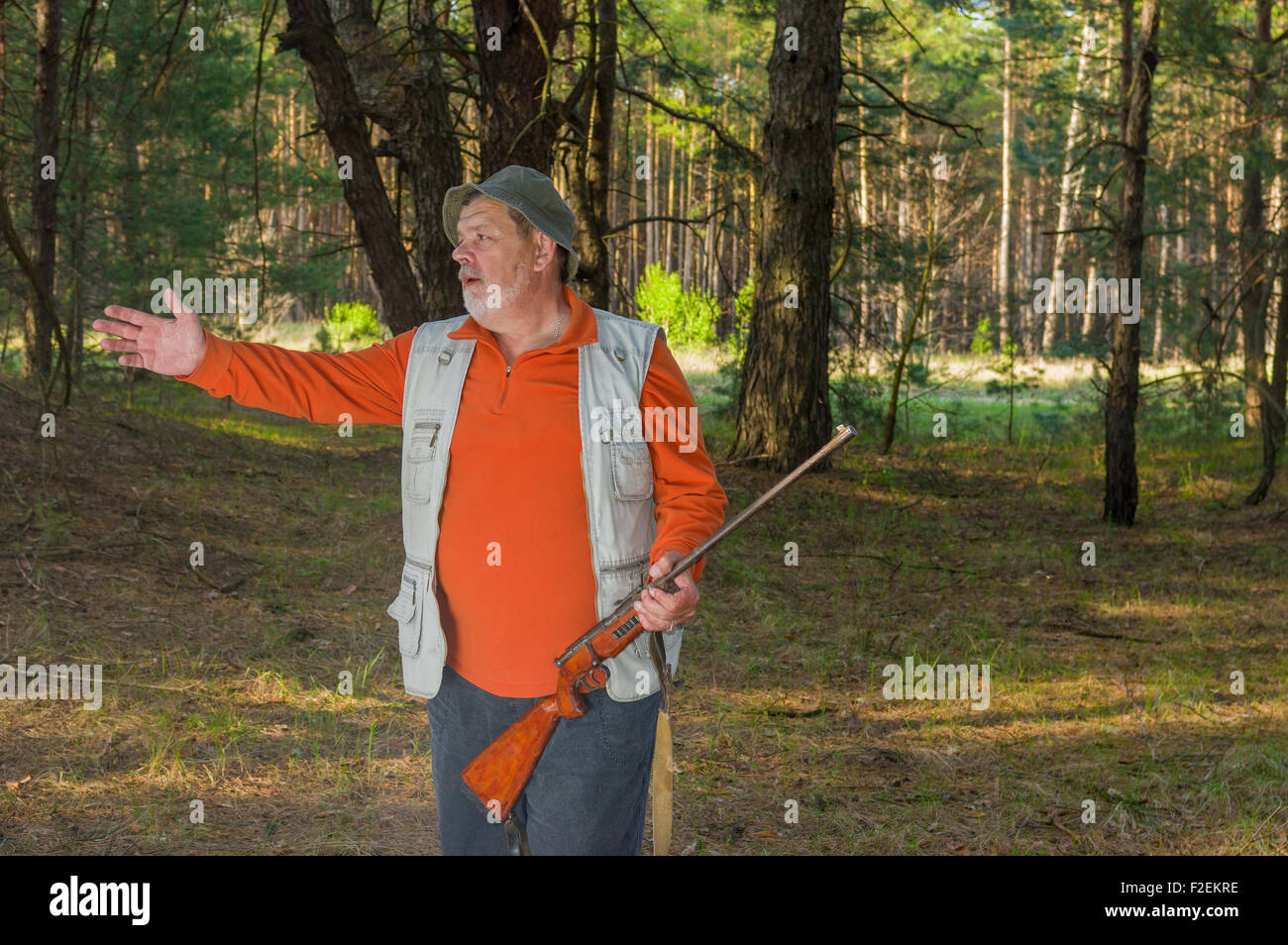 Rangers Senior avec carabine gesticule en forêt sombre Banque D'Images