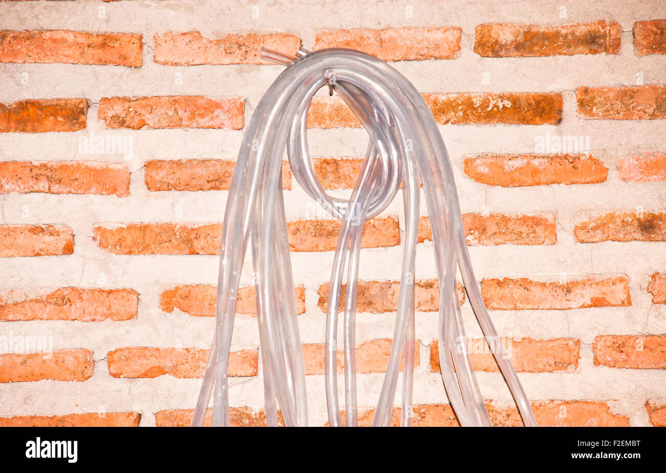 Tube en plastique pour mesurer le niveau d'eau sur un mur de briques. Banque D'Images