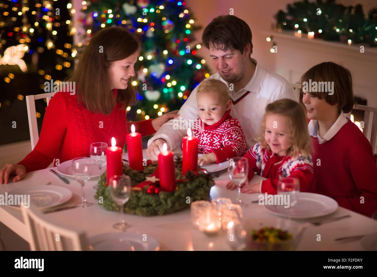 Grande famille avec trois enfants célébrer Noël à la maison. Dîner de fête à cheminée et arbre de Noël. Parent et enfant de manger Banque D'Images