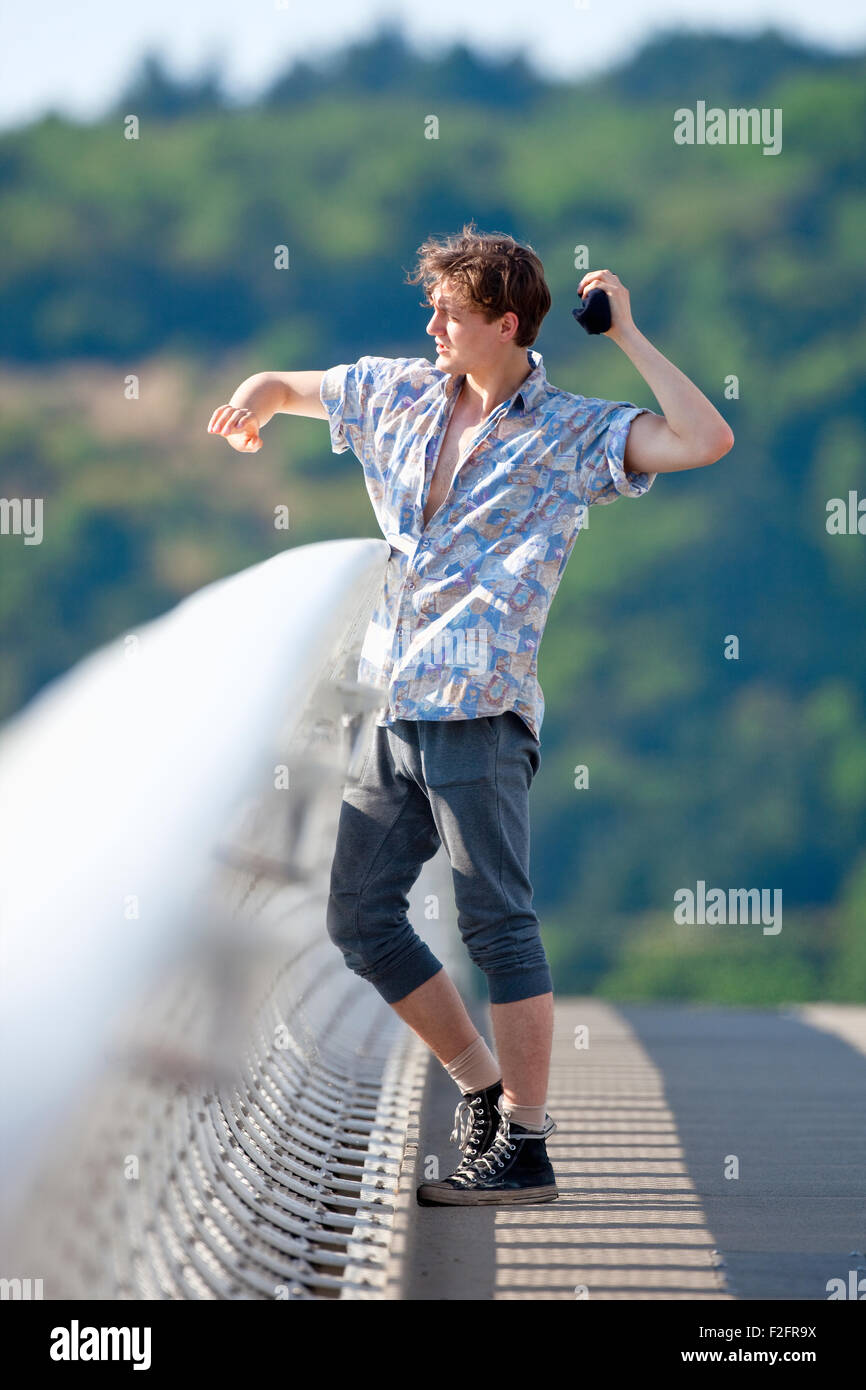 Jeune homme debout sur le pont de jeter quelque chose vers le bas Banque D'Images