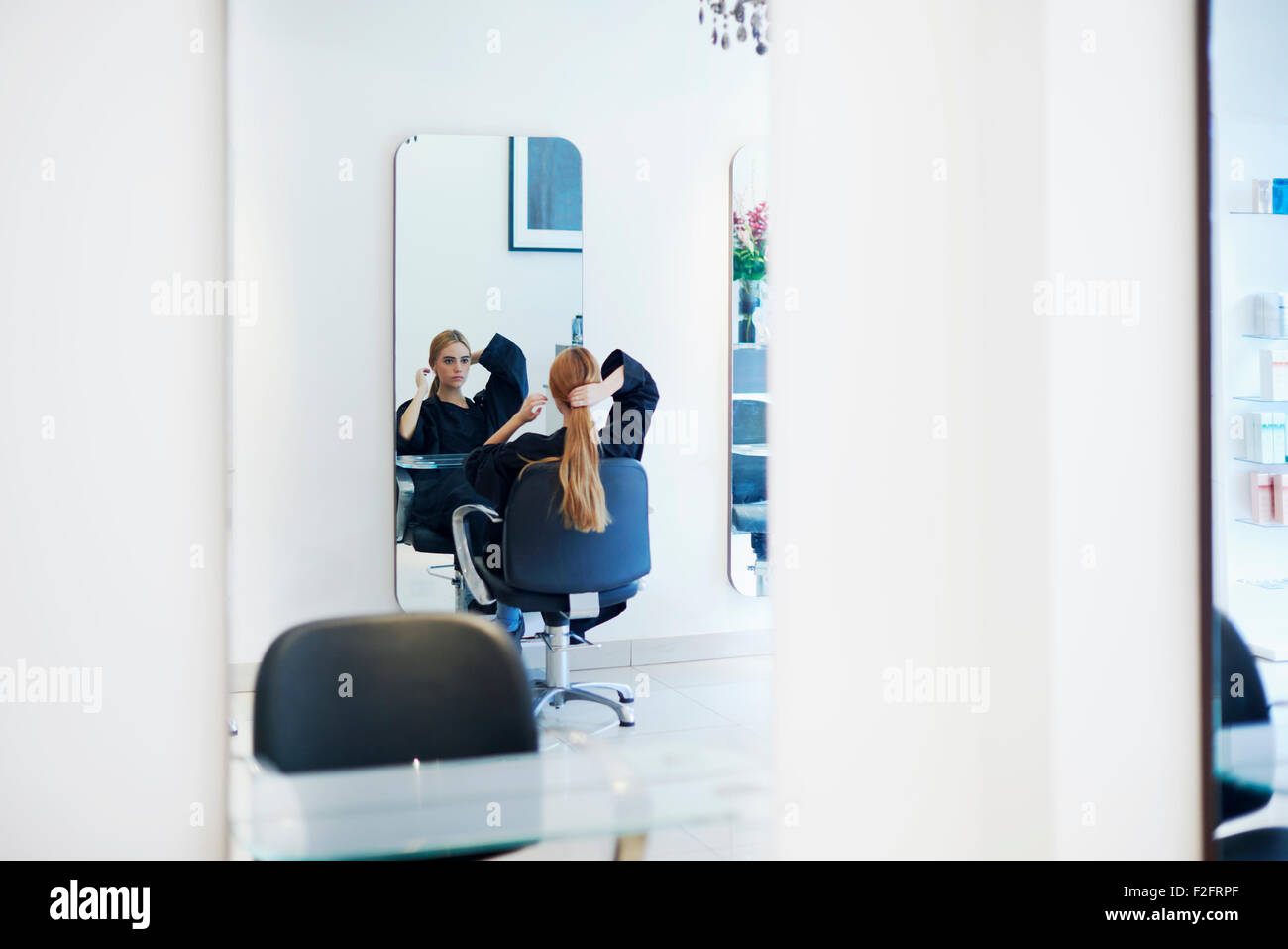 Client avec de longs cheveux à la recherche en miroir dans un salon de coiffure Banque D'Images
