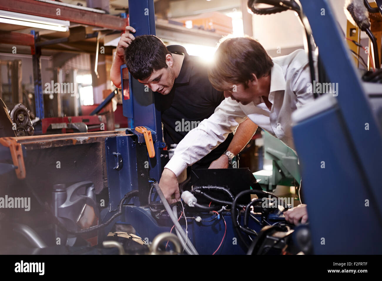 Mécaniciens travaillant sur voiture en atelier de réparation automobile Banque D'Images