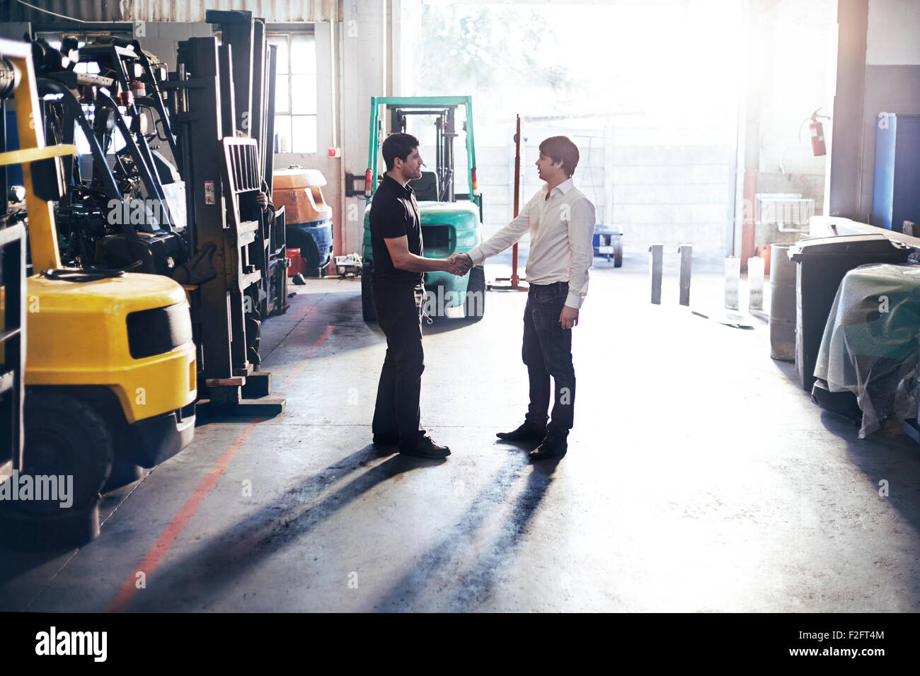 Mécanicien et client handshaking in auto repair shop Banque D'Images