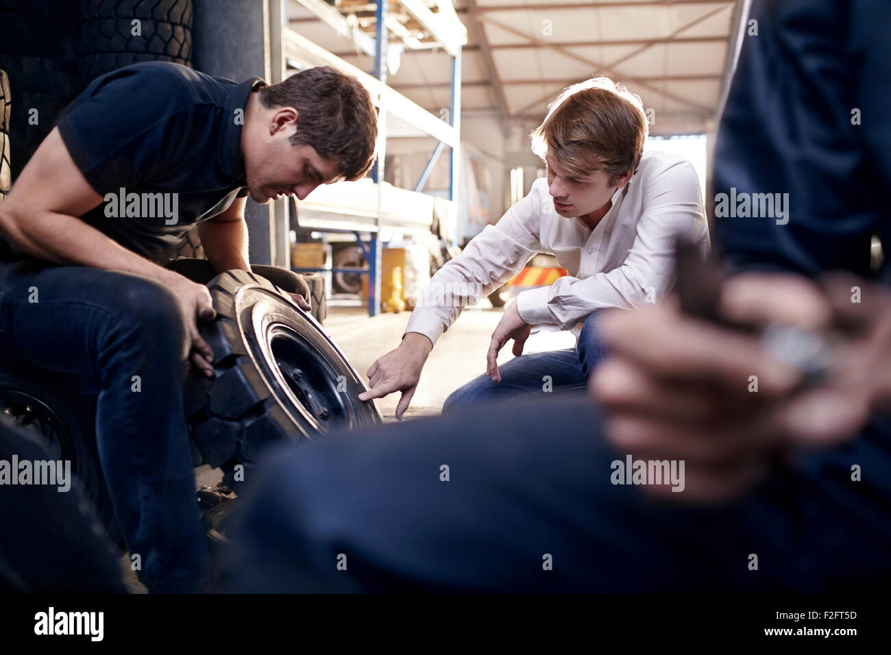 Mécanicien et de l'examen du client dans des pneus auto repair shop Banque D'Images