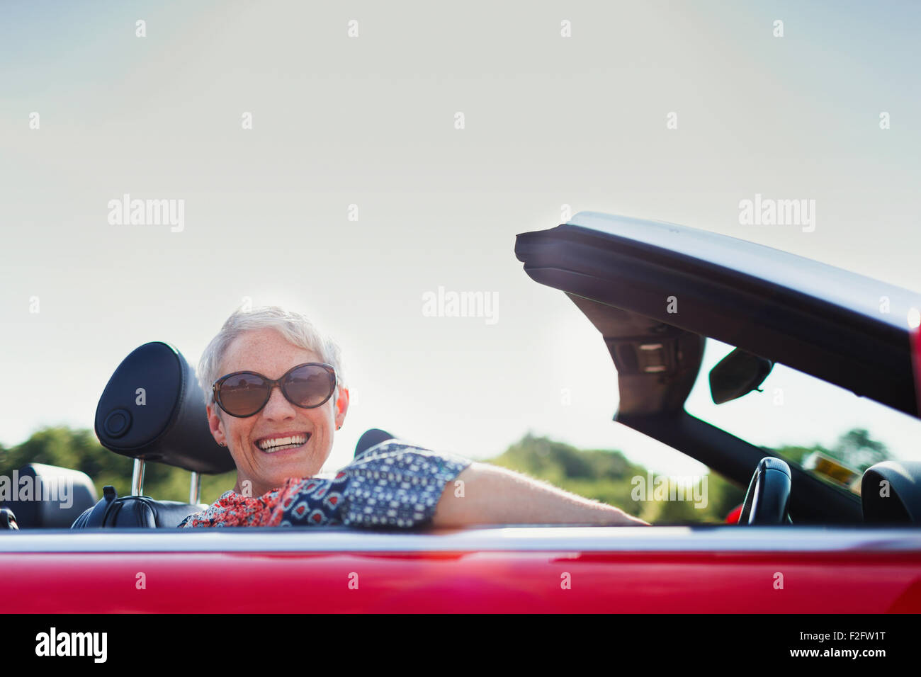 Portrait of senior woman driving red cabriolet Banque D'Images