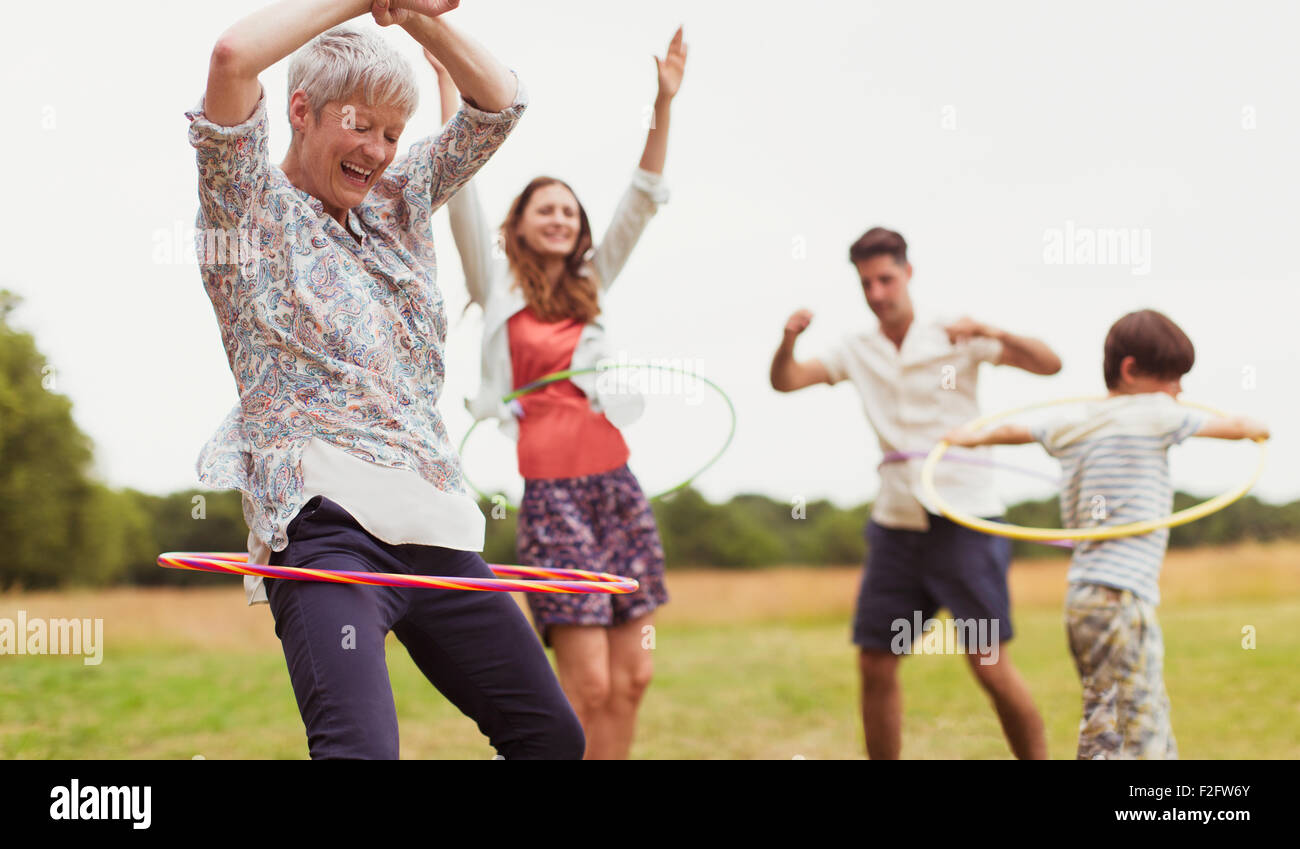 Multi-generation family ludique de la vrille en plastic hoops in field Banque D'Images