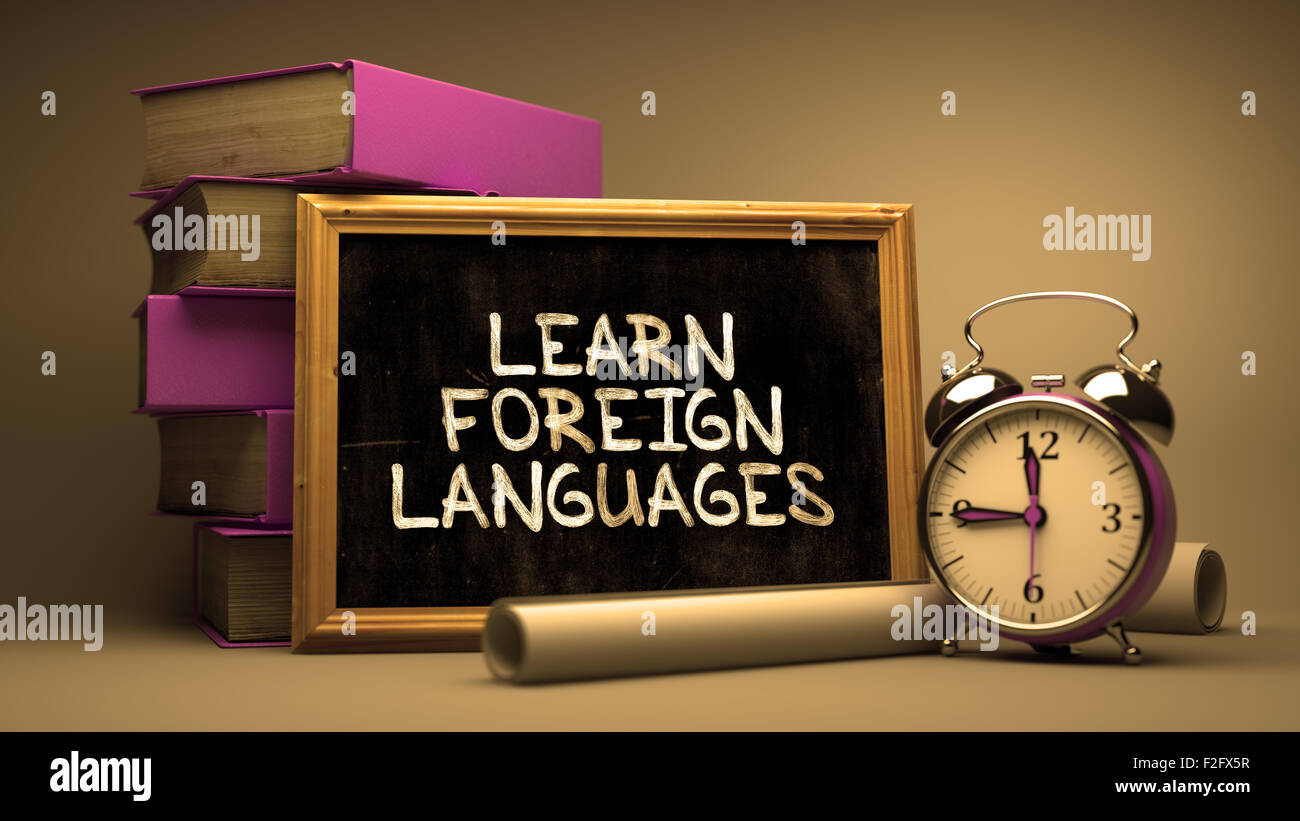 Apprendre les langues étrangères à la main sur tableau. Concept de temps. La composition avec tableau noir et pile de livres, Réveil et Banque D'Images