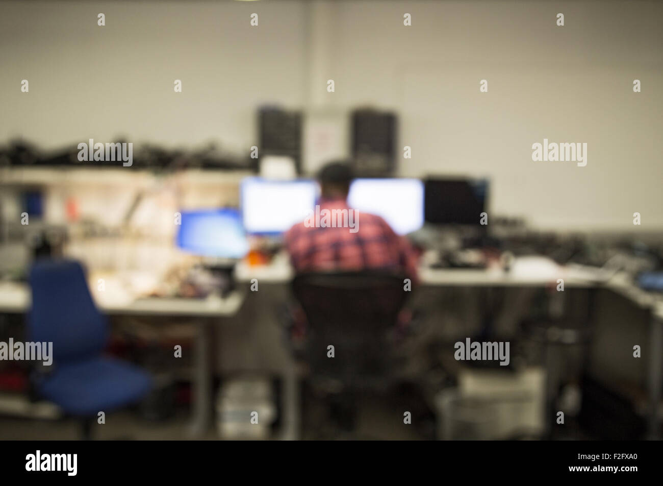 Des problèmes de mise au point d'un homme travaillant dans un centre de réparation d'ordinateur, des pièces d'ordinateurs et écrans tout autour de lui Banque D'Images