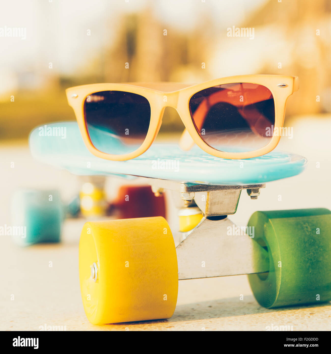 Lunettes de soleil sur la carte blue penny avec roues multicolores devant les palmiers Banque D'Images