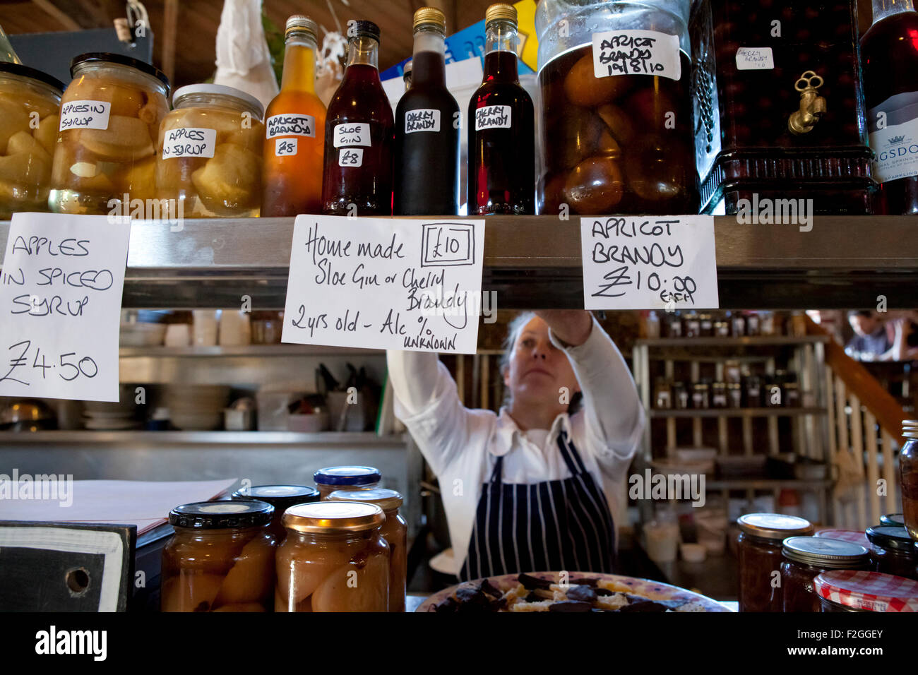 Une dame réapprovisionnement des rayons avec des produits frais dans un marché de producteurs à Canterbury. Banque D'Images