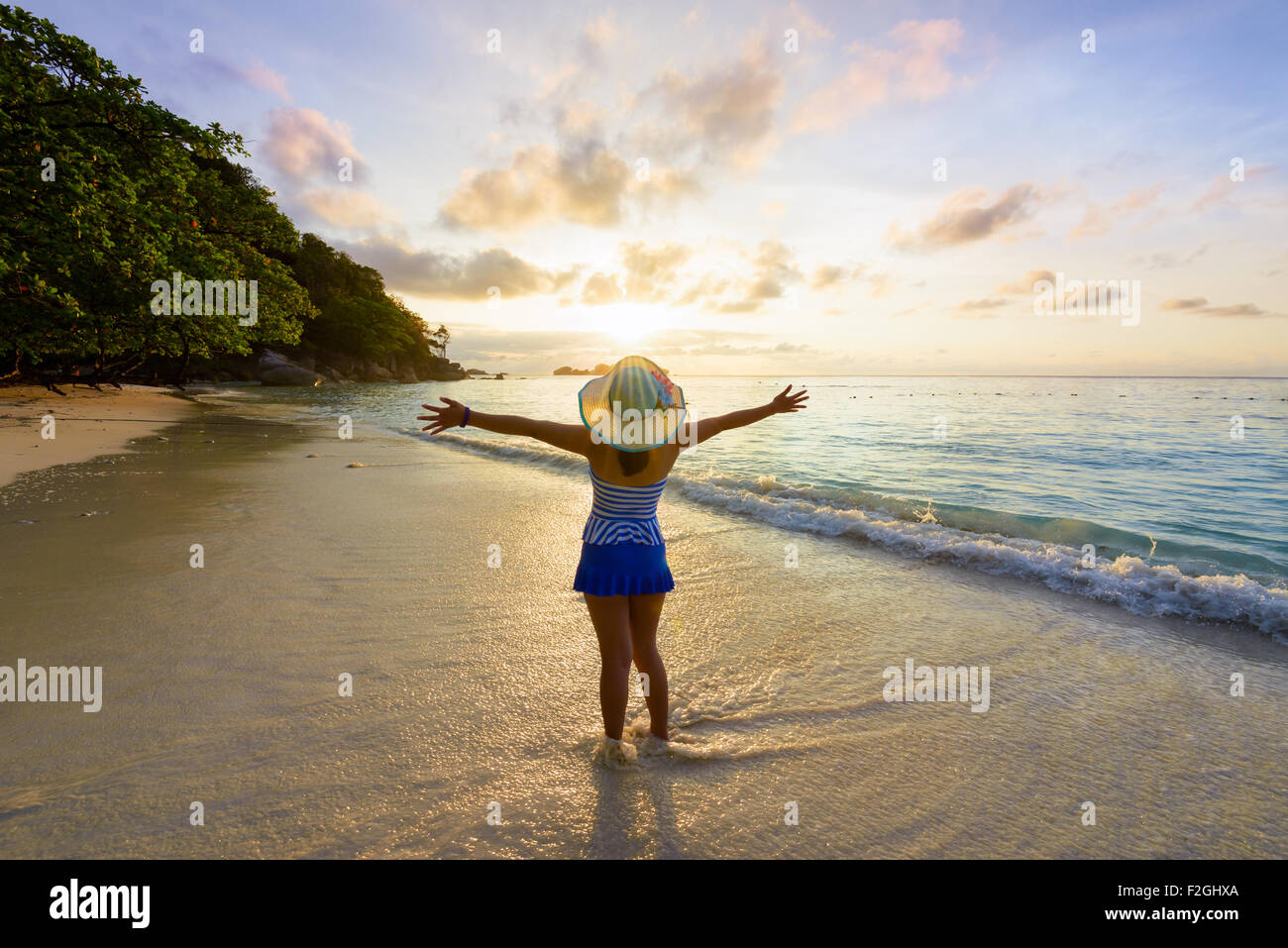 Fille de tourisme dans un maillot rayé bleu et blanc hat standing on beach avec plaisir le beau paysage de ciel et mer Banque D'Images
