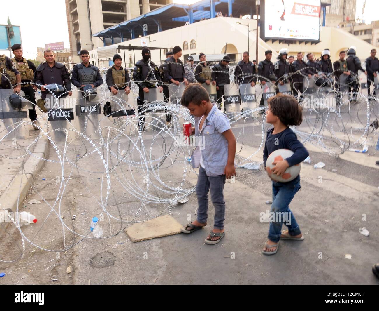 Bagdad, Iraq. 18 Sep, 2015. Deux enfants se tenir devant les forces de sécurité irakiennes dans une rue pendant une manifestation contre la corruption et une mauvaise qualité des services en ce qui concerne les coupures de courant et des pénuries d'eau, à la place Tahrir, dans le centre de Bagdad, Iraq, 18 Septembre, 2015. © Khalil Dawood/Xinhua/Alamy Live News Banque D'Images