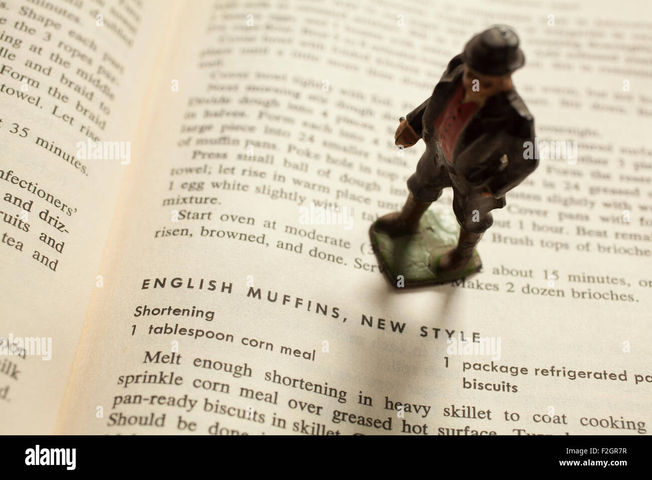 Un plomb antique toy gentleman anglais pose sur un vieux livre de cuisine. Banque D'Images