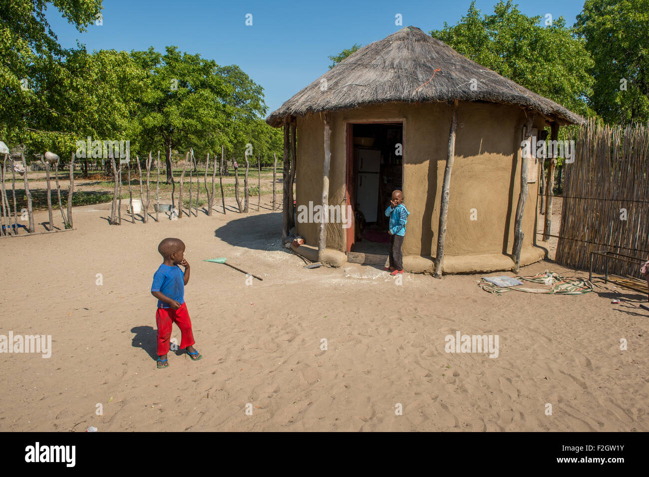 Les enfants africains jouer en face d'une hutte au toit de chaume au Botswana, l'Afrique Banque D'Images