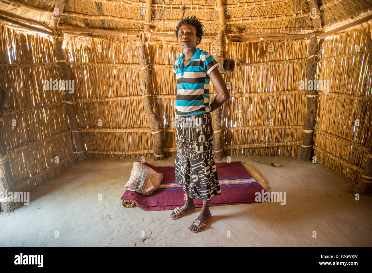 Sexaxa Village femme africaine se tenant debout à l'intérieur Hutte de chaume au Botswana, l'Afrique Banque D'Images