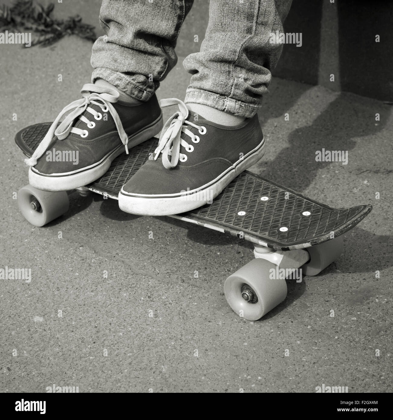 Adolescent pieds de jeans et gumshoes sur une planche à roulettes Banque D'Images