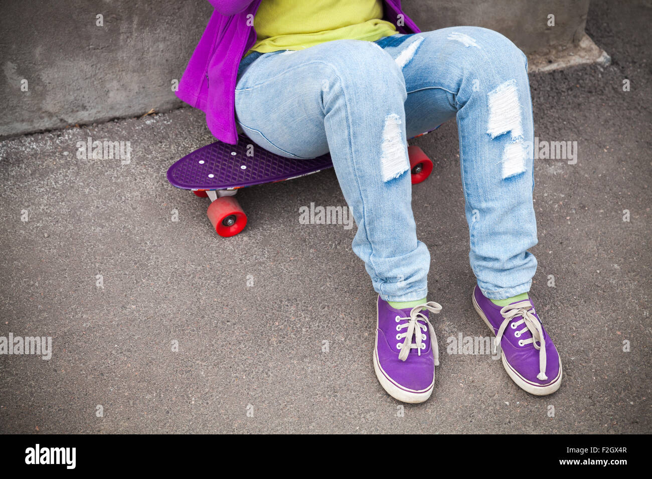 Adolescent en jeans et gumshoes siège sur roulettes Banque D'Images