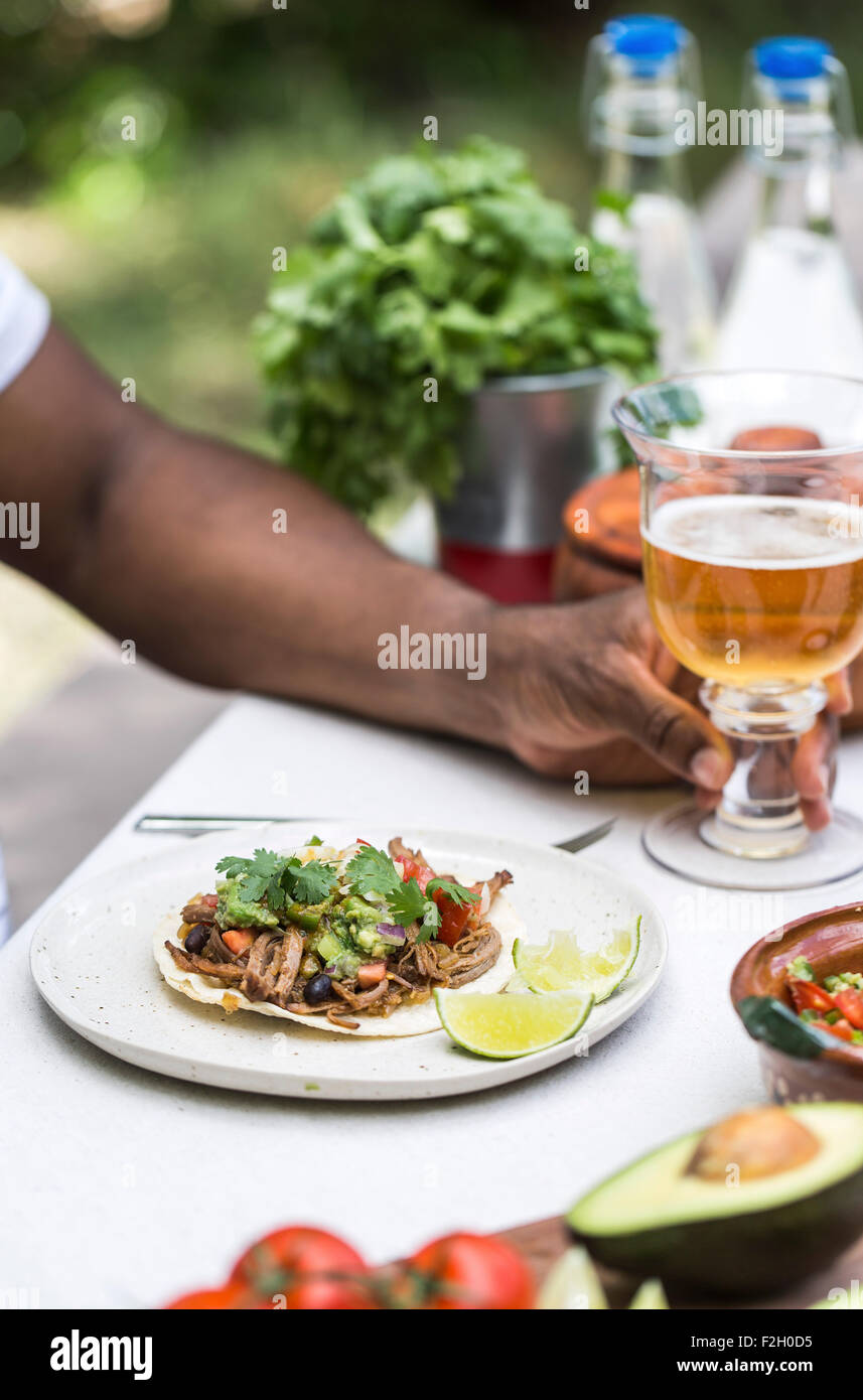 Une poitrine de boeuf mijotés chili taco a servi à une personne dans une table de pique-nique avec de la bière. Banque D'Images