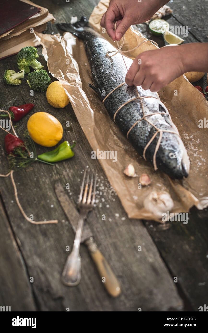 Attachant une corde sur le poisson pour la cuisson. Papier cuisson Banque D'Images