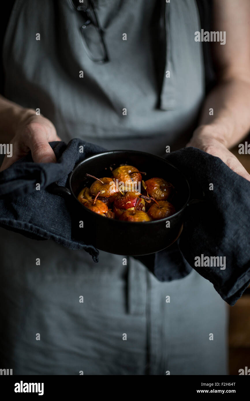 Homme avec tablier de cuisine cocotte rôti farci avec la tenue des pommes dans ses mains Banque D'Images