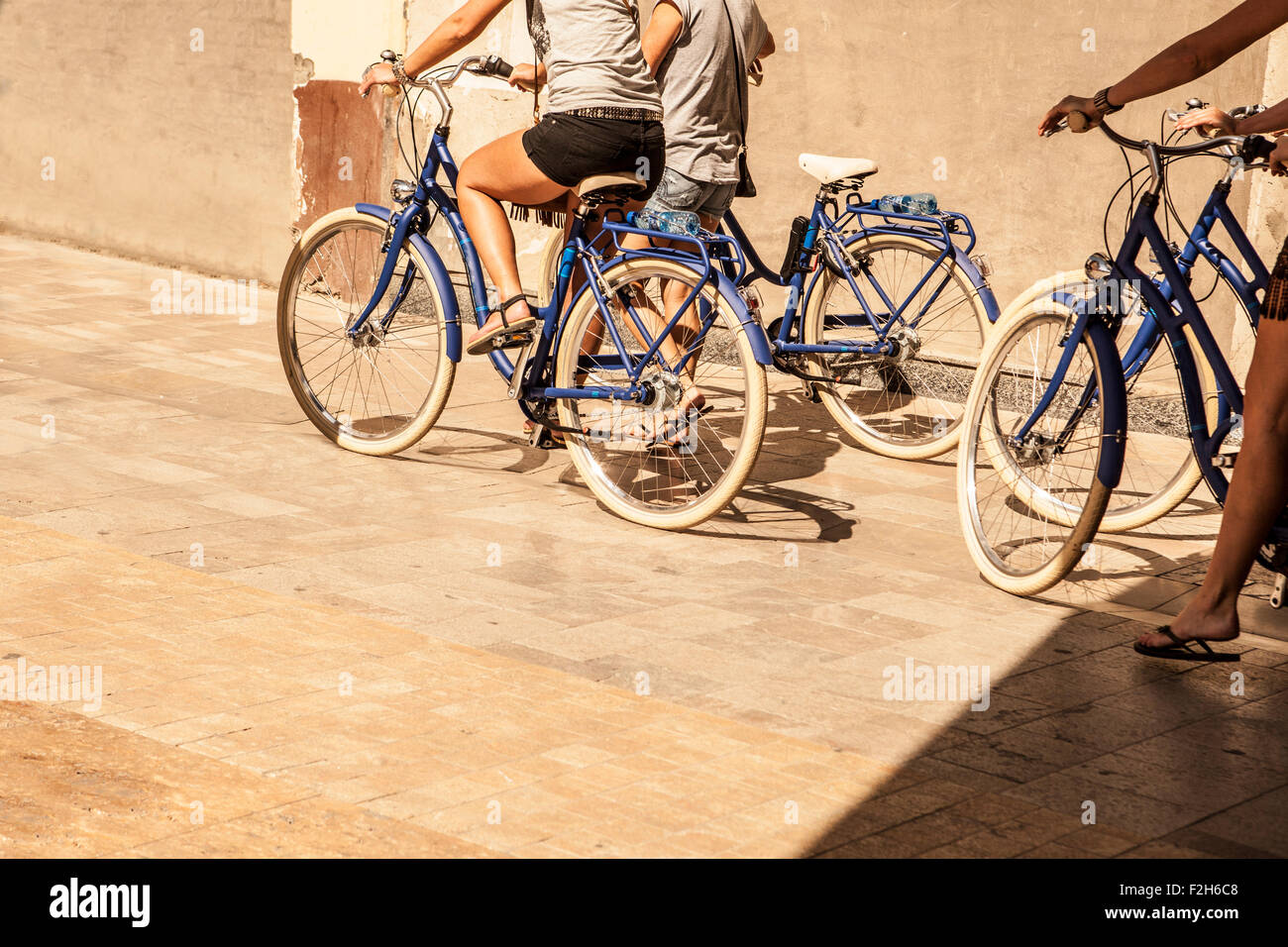 Quatre jeunes femmes marchant dans la ville avec les vélos. La vieille ville de Malaga Banque D'Images