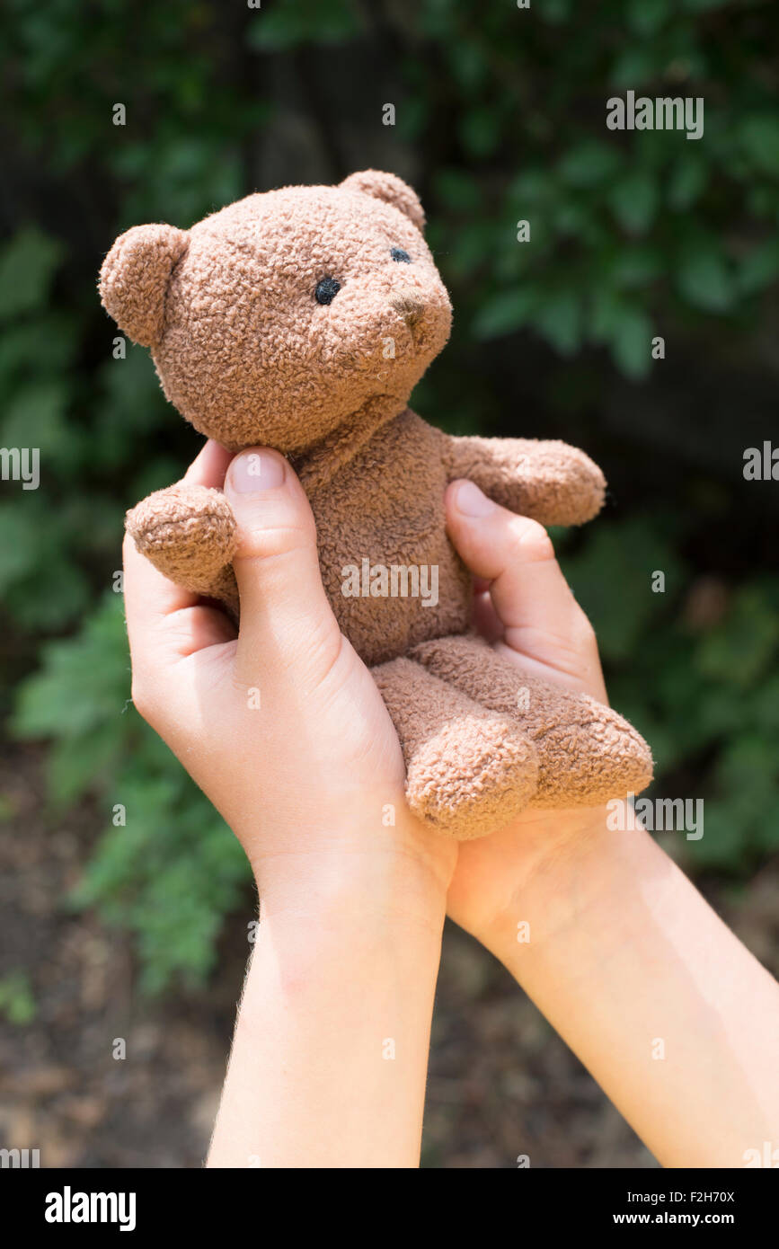 Maintenez l'enfant teddy dans un jardin. Banque D'Images