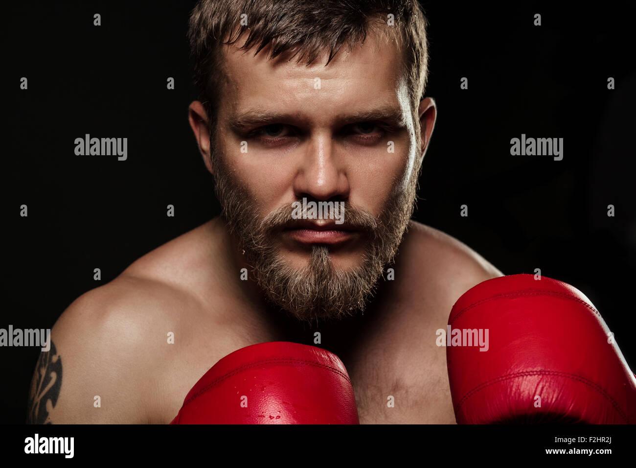 Athletic boxer barbu avec des gants sur fond sombre Banque D'Images