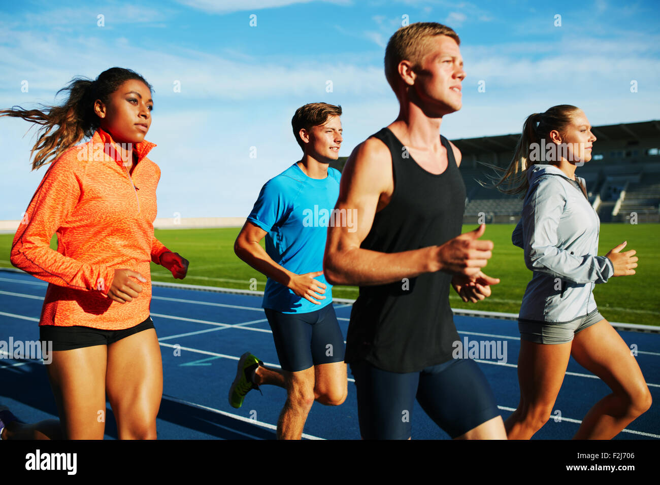 Groupe d'athlètes professionnels pratiquant multiraciale fonctionnant en stade. Athlètes masculins et féminins exécutant ensemble sur racetrack Banque D'Images Groupe d'athlètes professionnels pratiquant multiraciale fonctionnant en stade. Athlètes masculins et féminins exécutant ensemble sur racetrack Banque D'Images