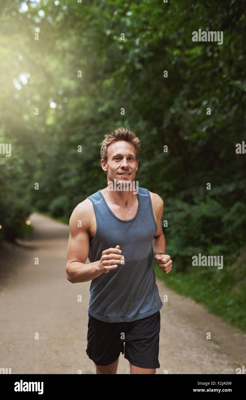Trois quart tourné d'un jeune homme athlétique en marche au parc dans la matinée. Banque D'Images