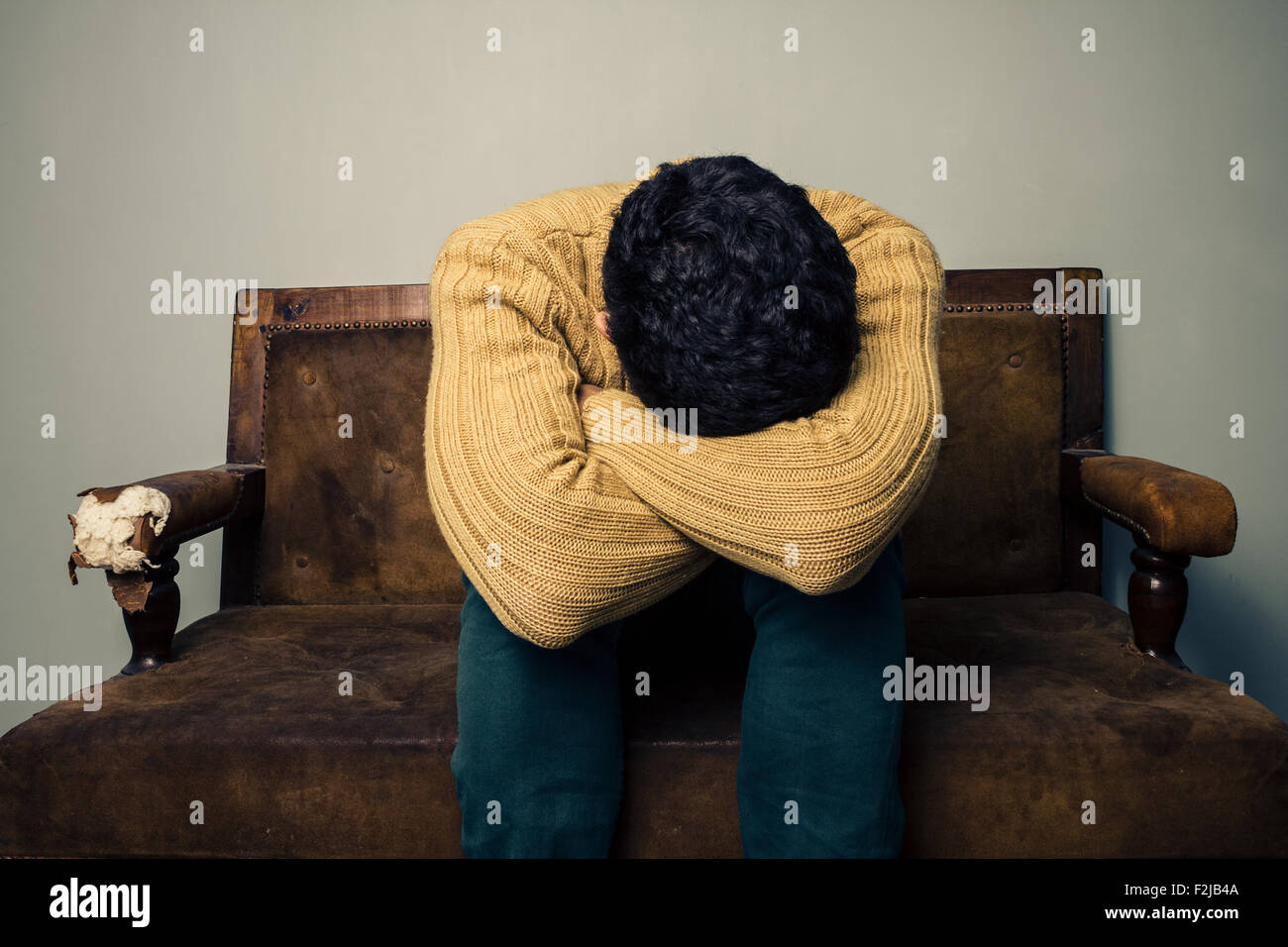 Sad young man sitting on sofa Banque D'Images