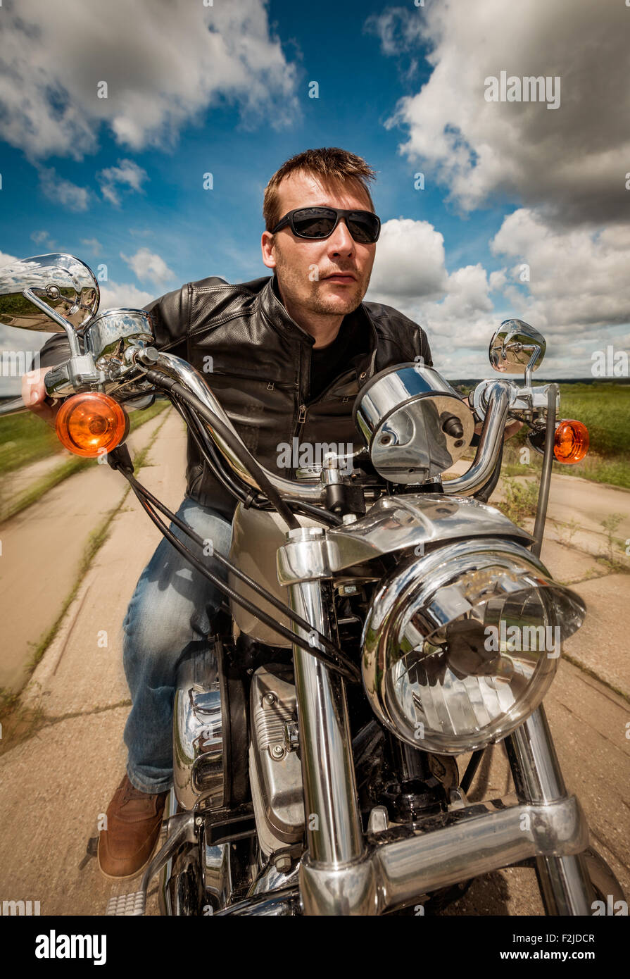Biker homme portant une veste en cuir et des lunettes de soleil assis sur  sa moto de course et sur la route Photo Stock - Alamy