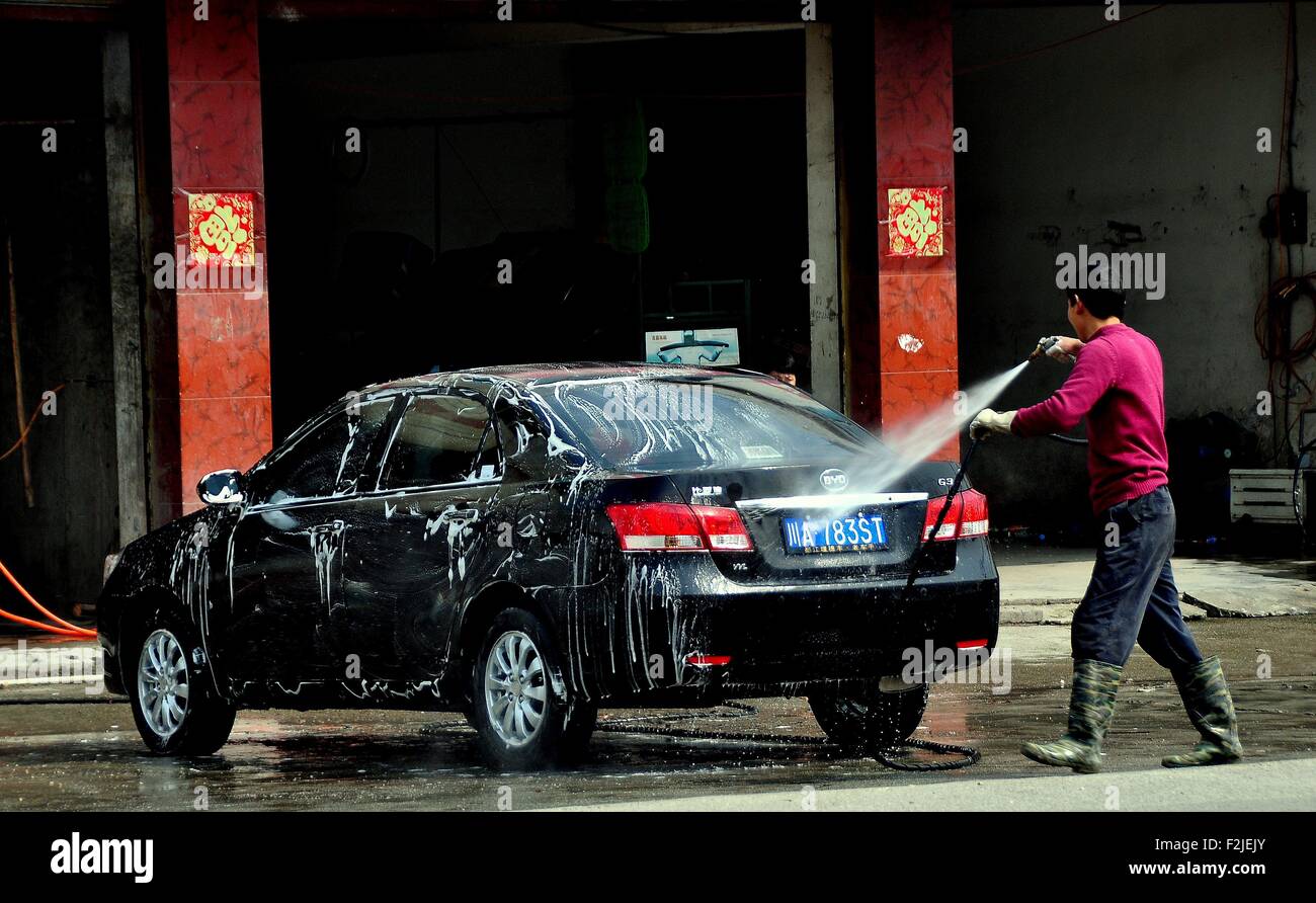 Long Feng, Chine : le travailleur à un lavage de voiture local boutique hoses duu au large de l'automobile d'un client à l'aide d'un flexible de haute puissance Banque D'Images