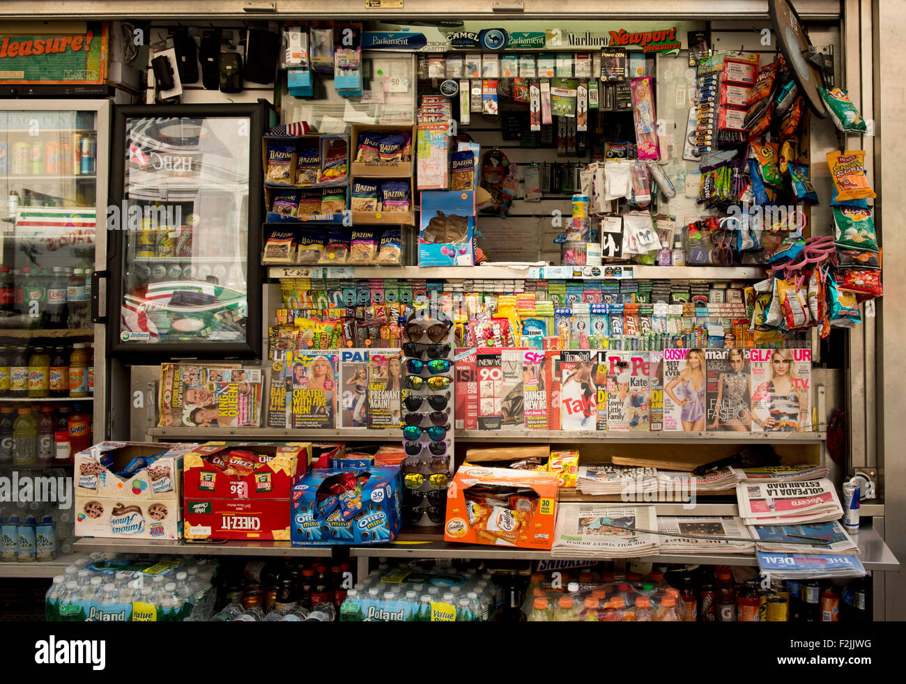 Un kiosque de Manhattan encombré à vendre des journaux, magazines, des collations, des boissons gazeuses, des lunettes de soleil et les cigarettes ; New York City Banque D'Images