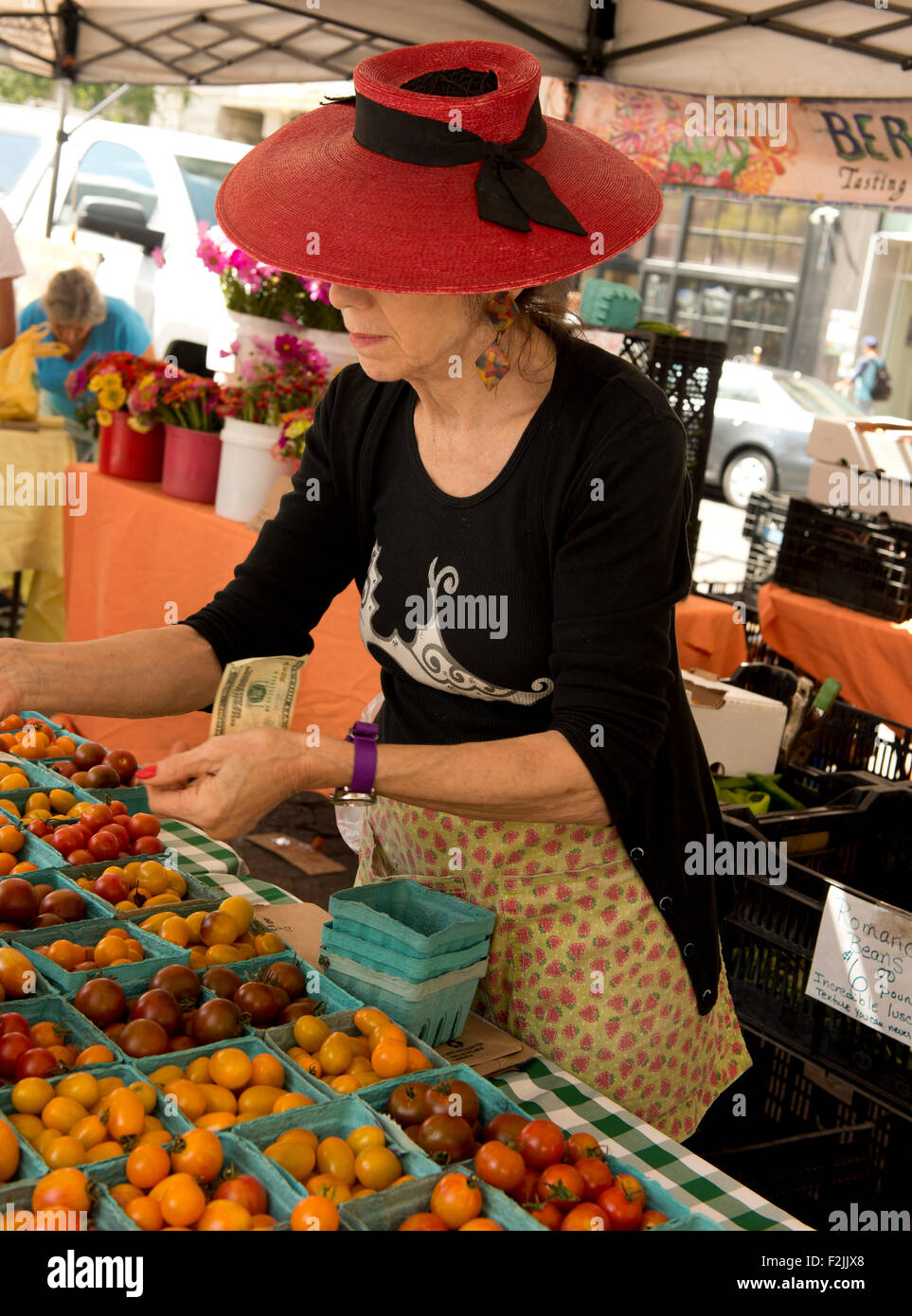 Une femme dans un chapeau de paille rouge tomates patrimoine vente à l'Union Square Market vente de produits agricoles à Manhattan, New York City Banque D'Images