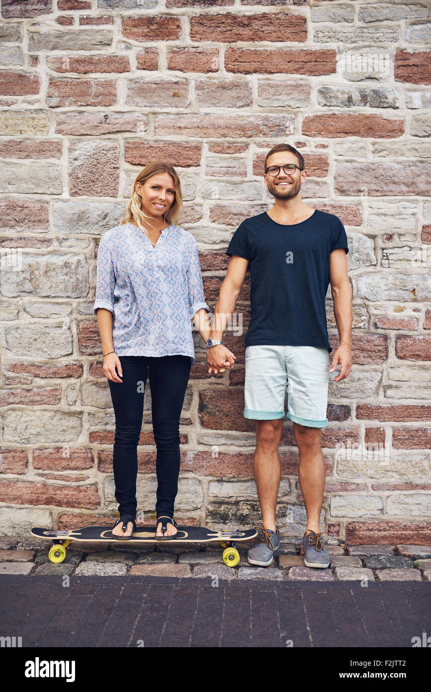 Young couple holding hand leaning against wall Banque D'Images