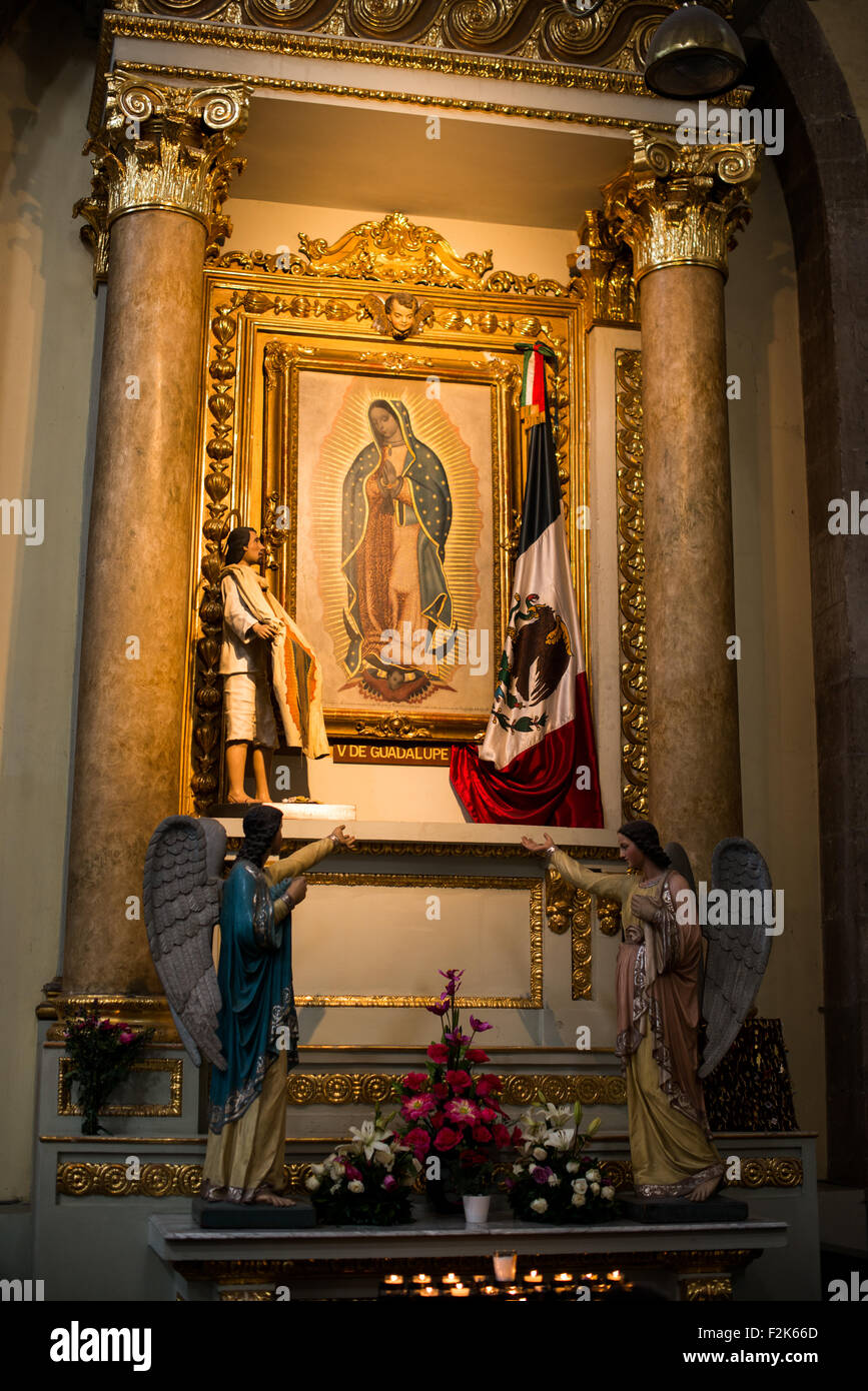 Peinture de notre-Dame de Guadalupe Metropolitan Tabernacle Mexico // MEXICO CITY, Mexique — Une peinture représentant notre-Dame de Guadalupe orne le mur d'une petite chapelle latérale à l'intérieur du Metropolitan Tabernacle (Sagrario Metropolitano). Le tabernacle de style baroque a été construit par l'architecte Lorenzo Rodríguez entre 1749 et 1760, à côté de la cathédrale métropolitaine face au Zócalo. Conçu à l'origine pour abriter les archives et les vêtements de l'archevêque, le bâtiment a également servi de lieu aux paroissiens pour recevoir l'Eucharistie et s'inscrire auprès de l'église. Le tabernacle con Banque D'Images