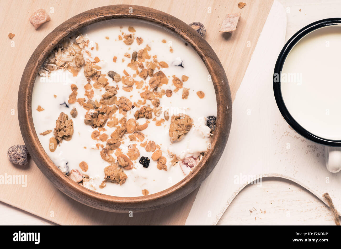 Muesli avec des fruits et des noix et du lait dans un bol en bois de style rustique Banque D'Images