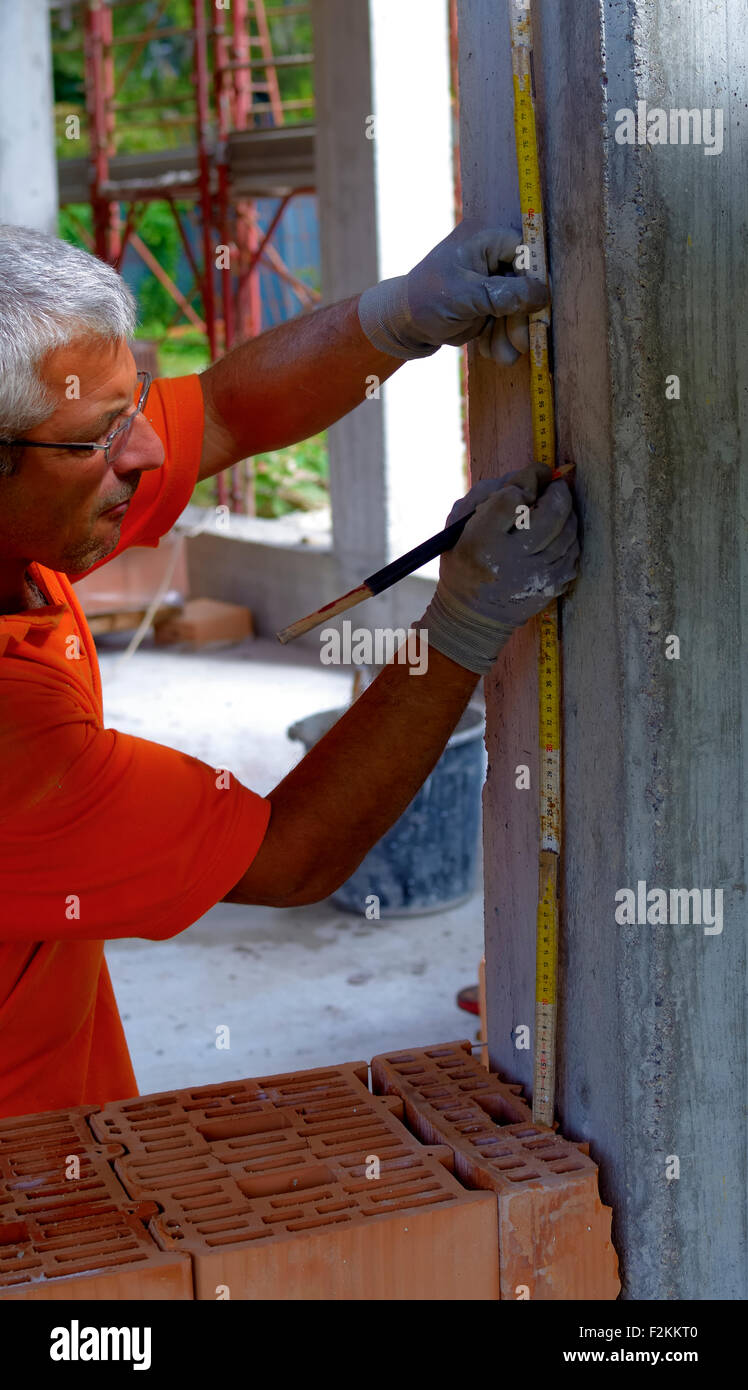 Travailleur avec crayon et règle de pliage de mètres une mesure sur un pilier en béton Banque D'Images