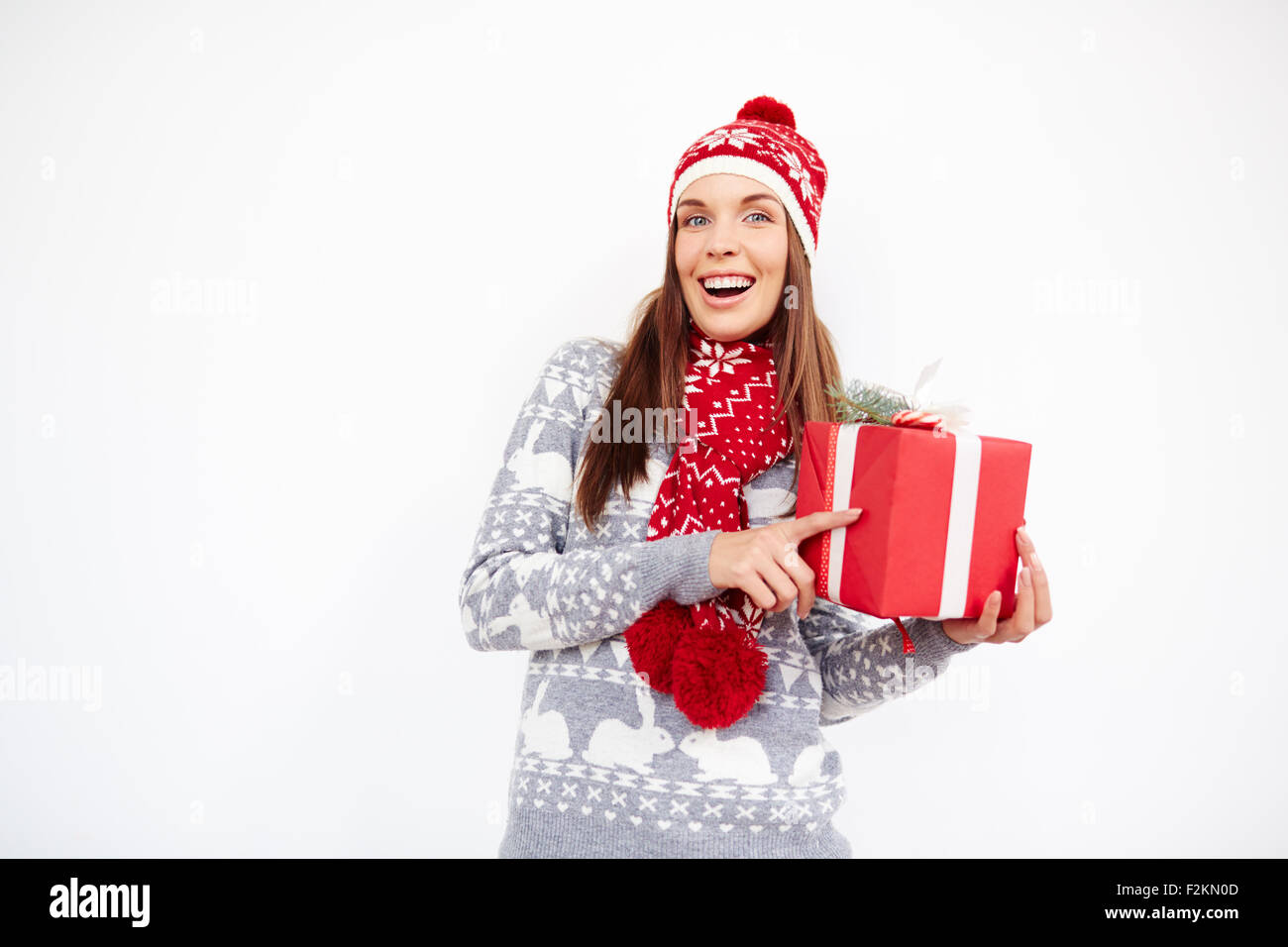 Surpris fille en cap, pull et écharpe holding red fort avec cadeau de Noël Banque D'Images