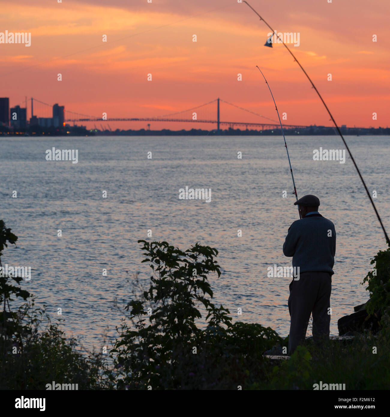 Detroit, Michigan - Un homme poissons dans la rivière Detroit au coucher du soleil. Banque D'Images